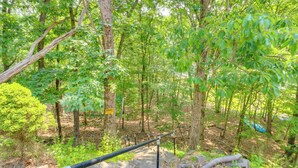 A wooden staircase leading into a forested area with a caution sign, surrounded by trees and natural scenery. - Gas Grill, Lake Access: Scenic Poconos Retreat! (East Stroudsburg)