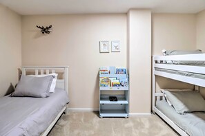 A bedroom with a single bed, a bunk bed, a bookshelf with children's books, and a deer head decoration on the wall. - Gas Grill, Lake Access: Scenic Poconos Retreat! (East Stroudsburg)