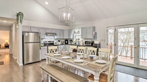 A modern kitchen with grey cabinets, stainless steel appliances, and a dining area set for six. - Gas Grill, Lake Access: Scenic Poconos Retreat! (East Stroudsburg)