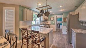 A kitchen with a central island, bar stools, hanging pots, and a refrigerator. - Idyllic Nampa Family Home With Hot Tub & Fire Pit! (Nampa)