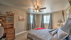 A bedroom with a bed, a ceiling fan, a dresser, and a window with curtains. - Idyllic Nampa Family Home With Hot Tub & Fire Pit! (Nampa)