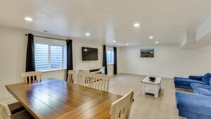 A modern living room with a wooden dining table, white chairs, a blue sofa, a TV, and a painting on the wall. - Sleek & Modern Morgan Abode: Great for Families! (Morgan)