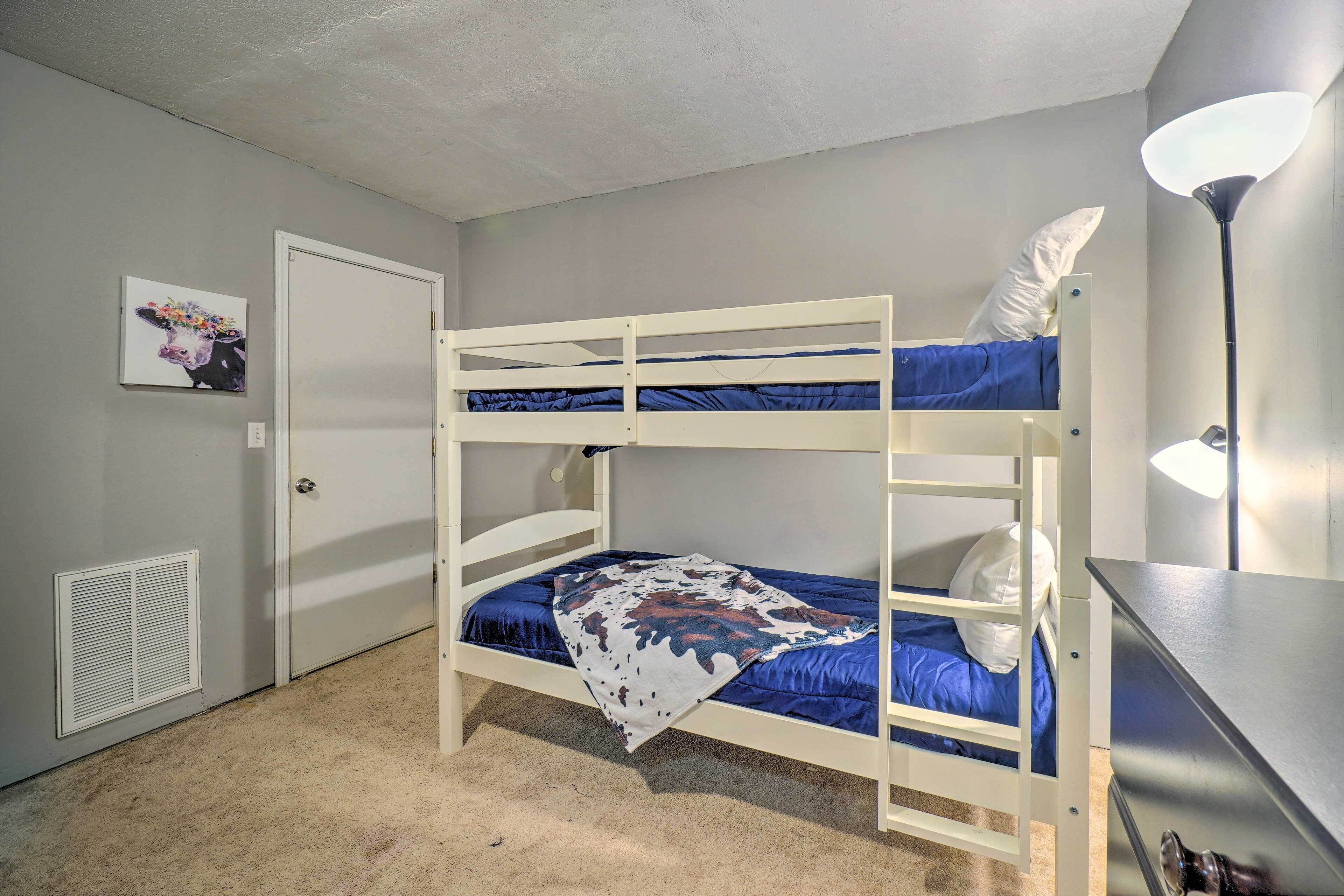 A bunk bed room with a door, a wall-mounted heater, and a desk with a lamp.