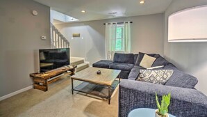 A living room with a sofa, a coffee table, a TV, and a staircase leading to another level. - Peaceful Sevierville Home w/ Private Hot Tub! (Sevierville)