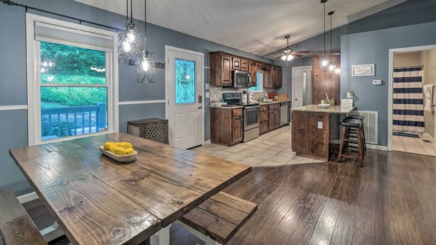 A kitchen with wooden cabinets, a central island, and a dining area with a bench. - Peaceful Sevierville Home w/ Private Hot Tub! (Sevierville)