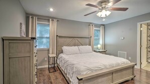 A bedroom with a bed, a ceiling fan, a nightstand, a dresser, and a window with curtains. - Peaceful Sevierville Home w/ Private Hot Tub! (Sevierville)