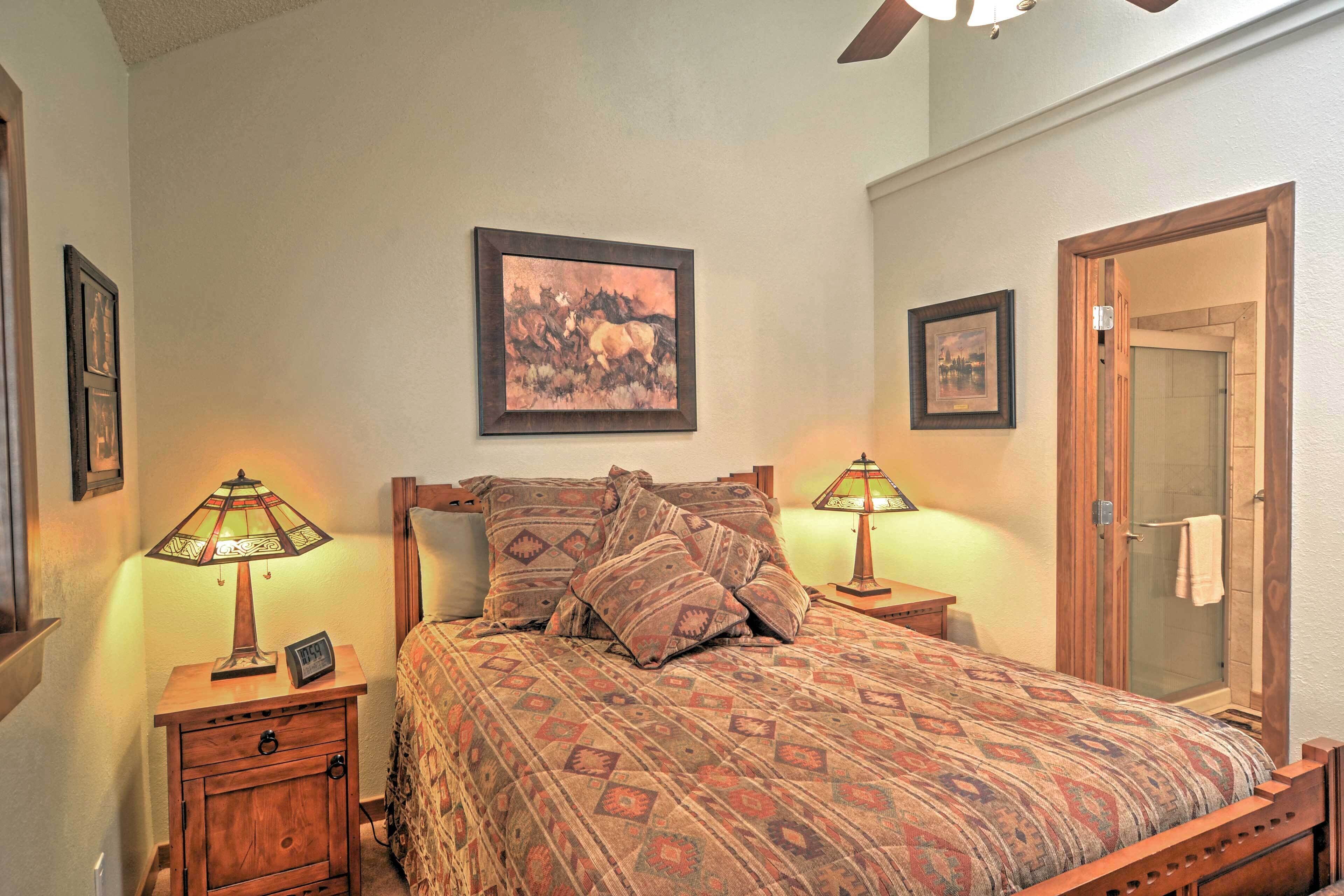 A bedroom with a bed, two nightstands with lamps, a wooden headboard, and two framed pictures on the wall.
