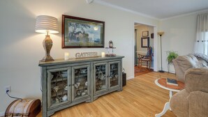 A living room with a wooden cabinet displaying china, a framed painting, and a 'GATHER' sign. - Deck & Pasture Views! Bealeton Farmhouse Escape (Bealeton)