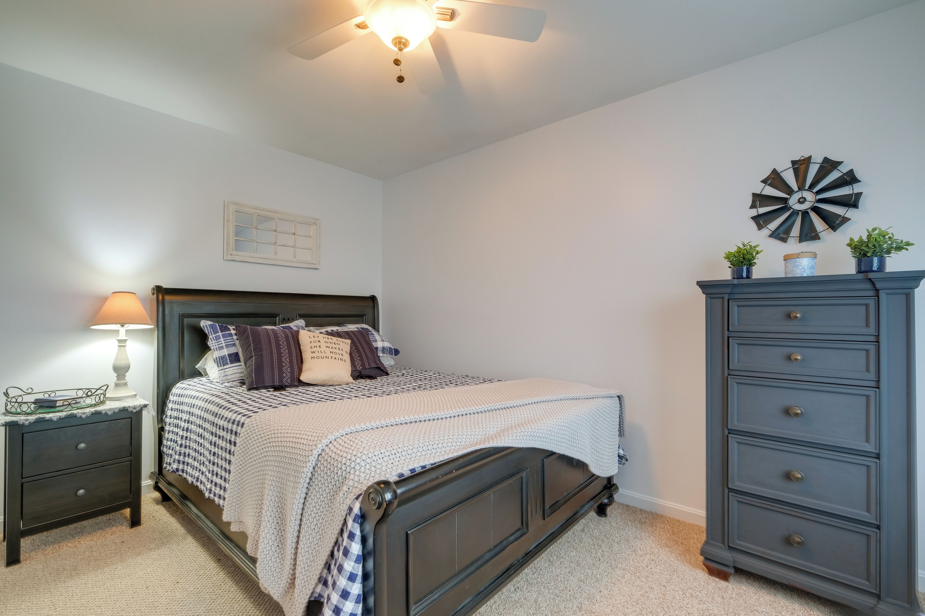A bedroom with a bed, nightstand, dresser, and a wall clock.