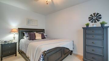 A bedroom with a bed, nightstand, dresser, and a wall clock.