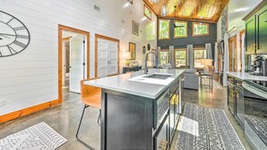 Una cocina amplia con una isla grande, techo de madera y ventanas grandes.