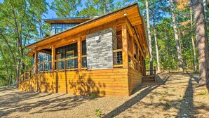 Una cabaña de madera con fachada de piedra, ventanas amplias y suelo de grava.