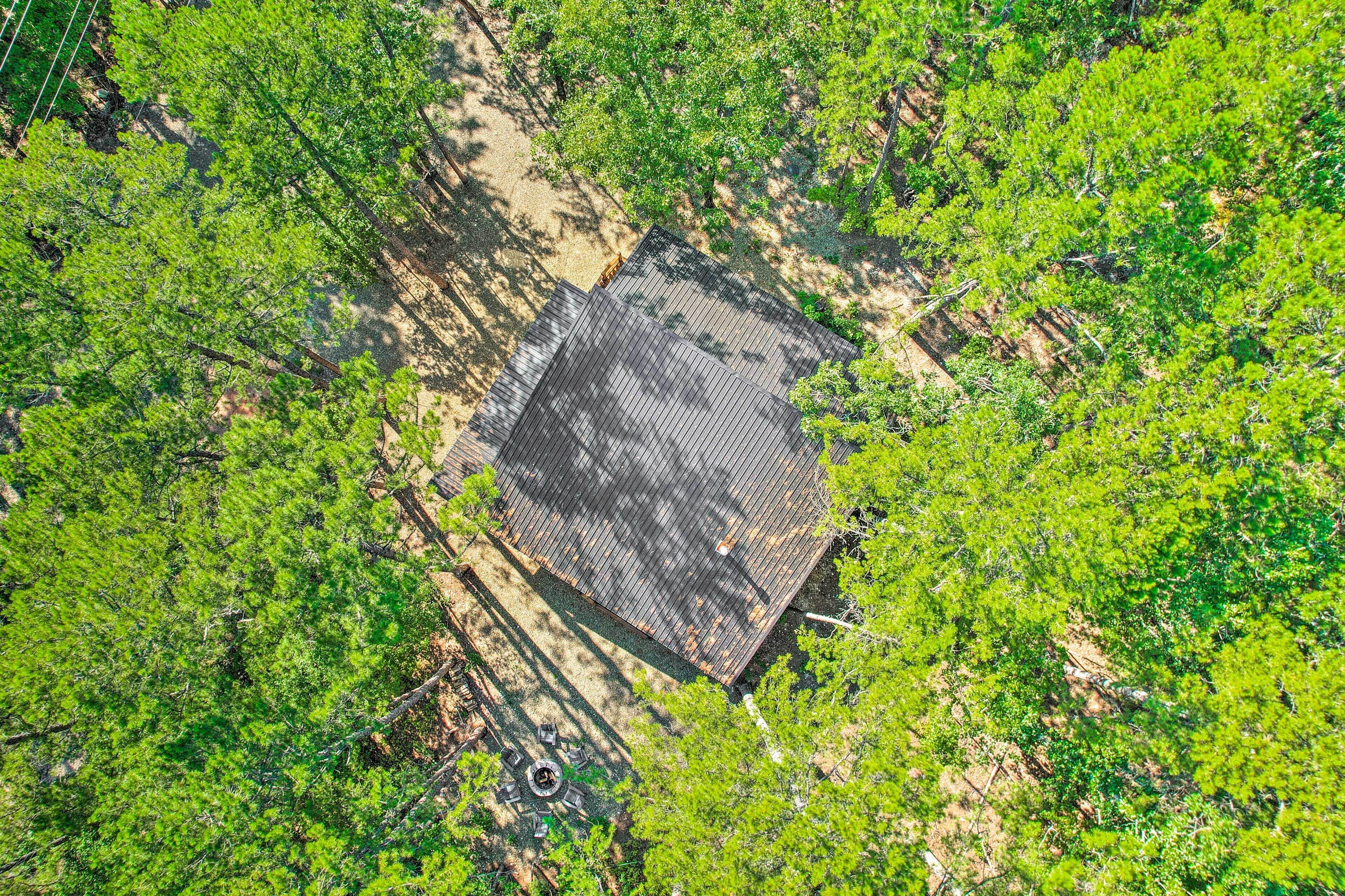 An aerial view of a square-shaped building surrounded by dense greenery.