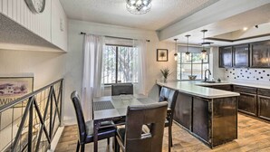 A modern kitchen with a central island, dark wooden flooring, and a dining area with a table and chairs. - Charming Santa Teresa Retreat w/ Backyard! (Santa Teresa)