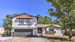 A two-story house with a garage, a small attached structure with a window, and a well-maintained lawn. - Charming Santa Teresa Retreat w/ Backyard! (Santa Teresa)