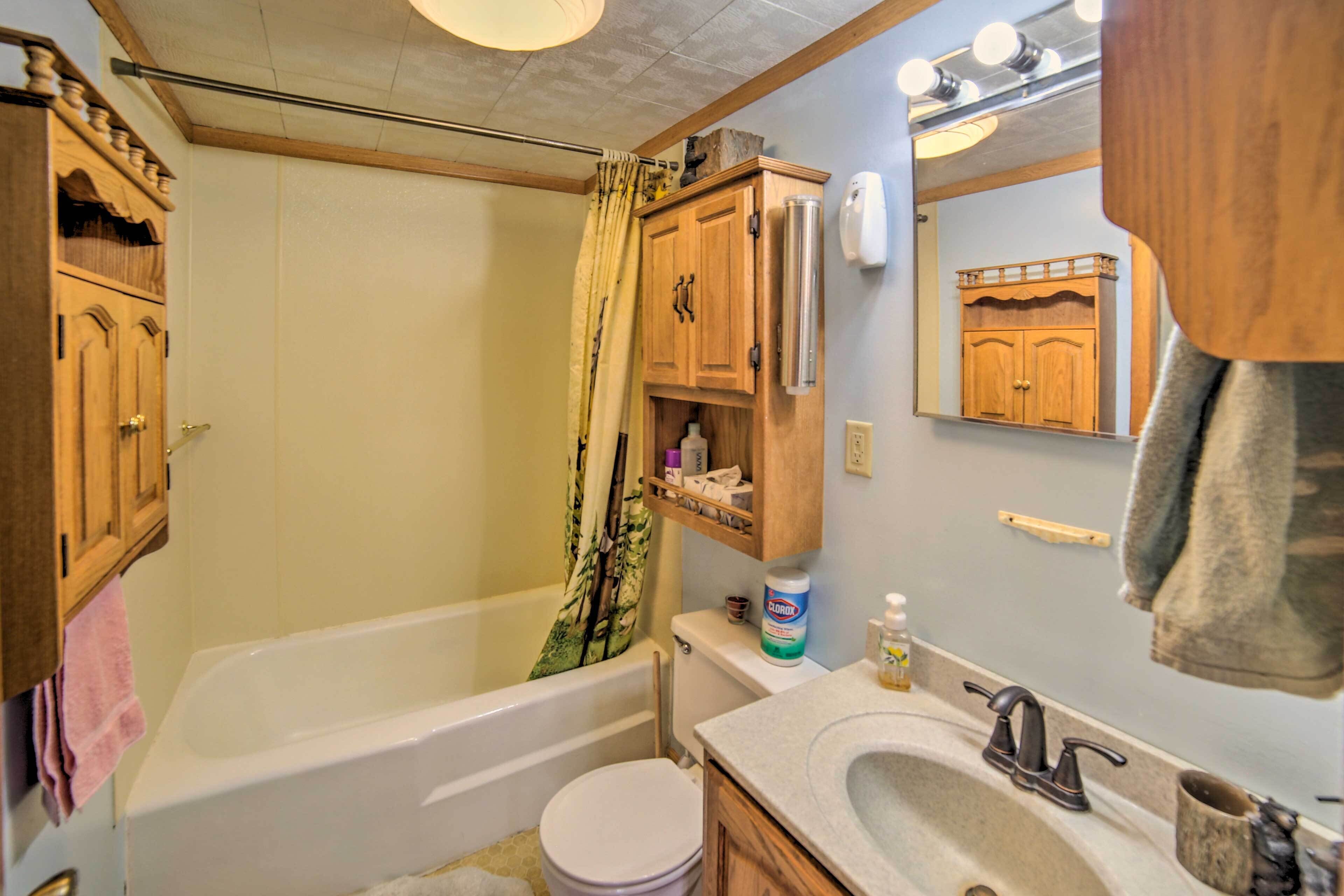 A bathroom with a bathtub, toilet, sink, and wooden cabinets.