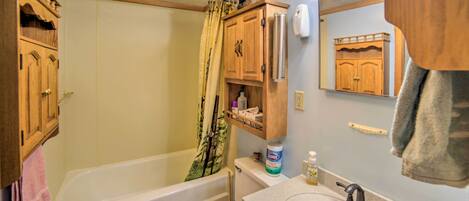 A bathroom with a bathtub, toilet, sink, and wooden cabinets.