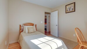 A bedroom with a bed, a wooden chair, a door, and a framed picture on the wall. - Tranquil Delmar Home ~ 7 Mi to Salisbury! (Delmar)