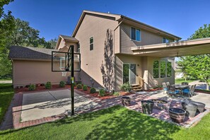 A residential house with a covered patio, outdoor seating, and a basketball hoop. - Spacious Omaha Home w/ Expansive Yard + Patio (Omaha)