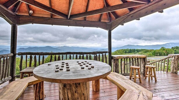 A wooden deck with a round table and stools, overlooking a mountainous landscape. - Family-friendly Burnsville Condo! Gated Community (Burnsville)
