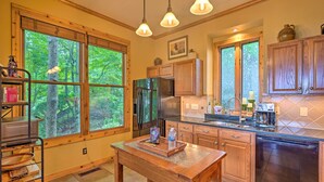 A kitchen with large windows, wooden cabinets, a stainless steel refrigerator, and a wooden dining table. - Family-friendly Burnsville Condo! Gated Community (Burnsville)