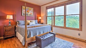 A bedroom with a four-poster bed, a bench, a dresser, and a large window offering a view of greenery. - Family-friendly Burnsville Condo! Gated Community (Burnsville)