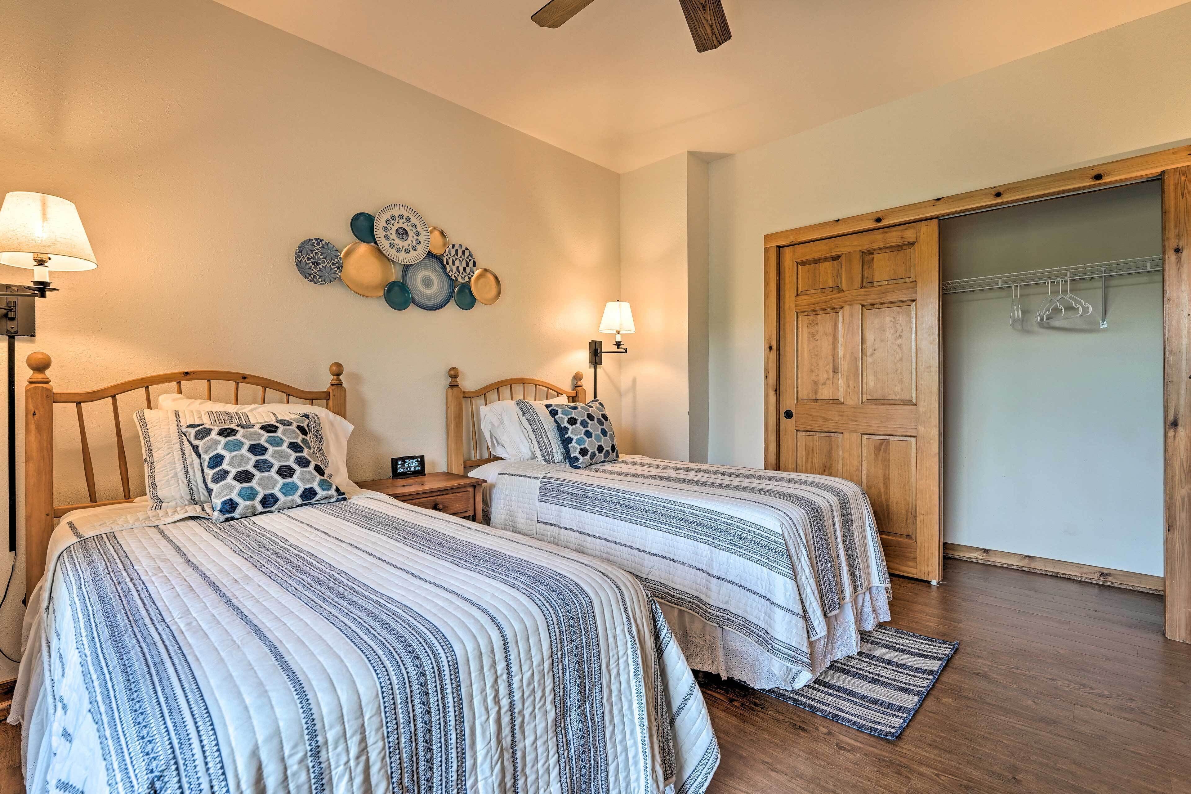 A bedroom with two beds, a wooden wardrobe, and a wall-mounted lamp.