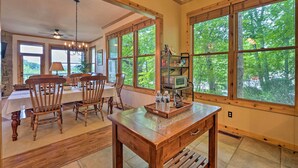 A spacious dining area with wooden chairs and a table, large windows with a view of trees, and a ceiling fan. - Family-friendly Burnsville Condo! Gated Community (Burnsville)