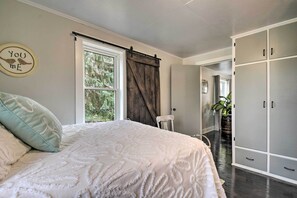 Een slaapkamer met een groot bed, een raam met gordijnen, een kledingkast en een wanddecoratie.