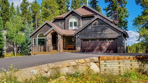 Une maison à deux étages, avec des fondations en pierre, un garage et une véranda à l’avant.