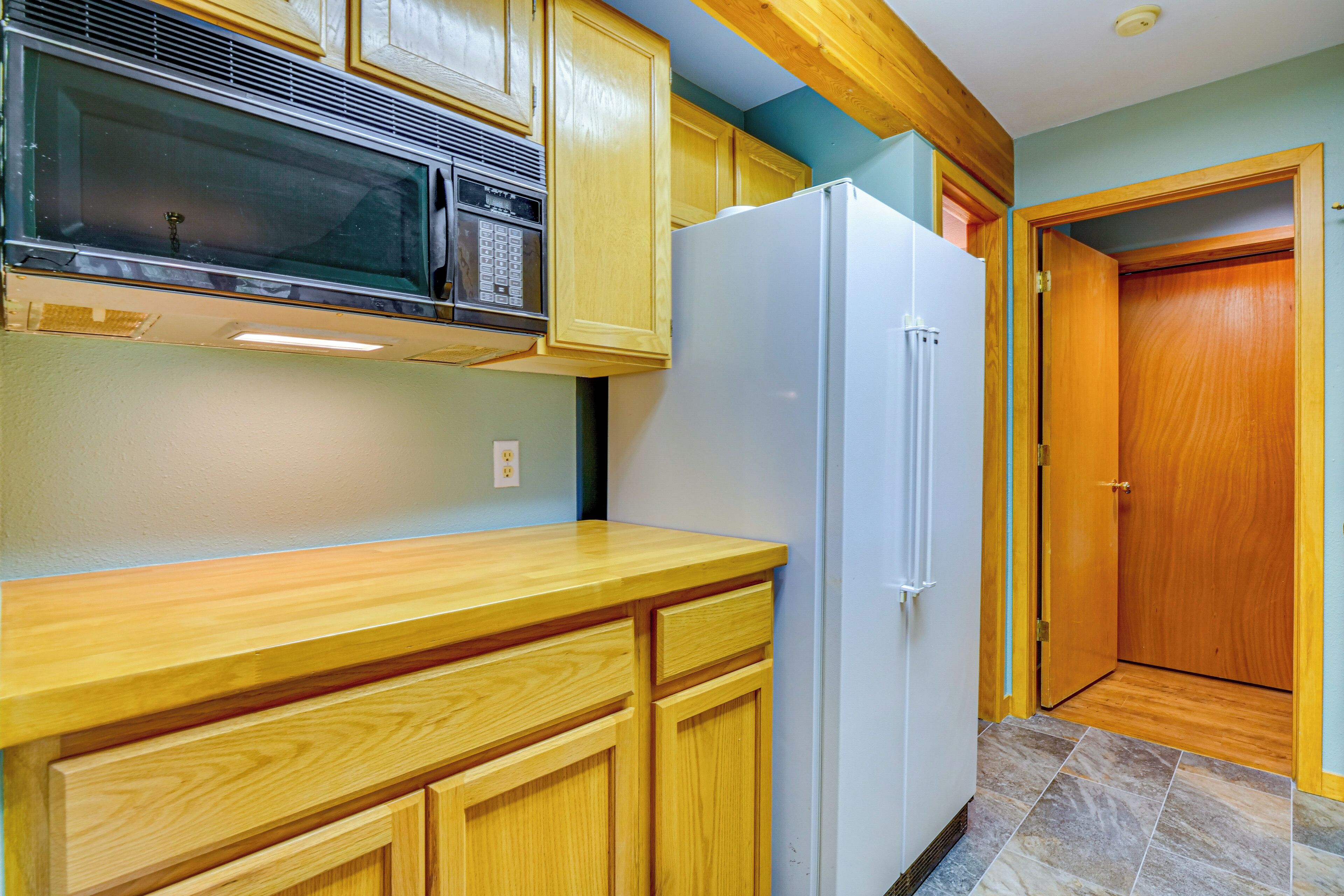 A kitchen with wooden cabinets, a microwave, and a refrigerator.