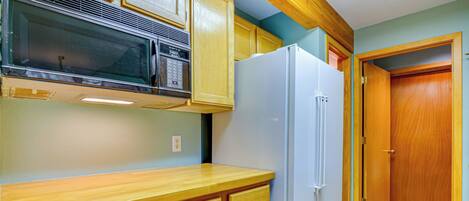 A kitchen with wooden cabinets, a microwave, and a refrigerator.