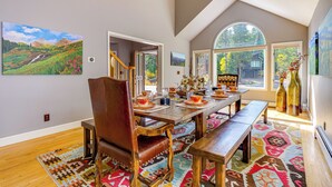 Un coin repas avec une table en bois dressée pour le repas, un banc et une chaise.