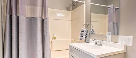Een badkamer met een douche, wastafel en spiegel.