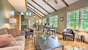 A spacious living room with a wooden ceiling, a dining area, and large windows offering a view of the outdoors. - Hike & Zip-line: Red River Gorge Cabin w/ Hot Tub! (Zoe)