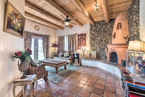 A rustic interior with a stone fireplace, wooden ceiling beams, and a traditional sofa.