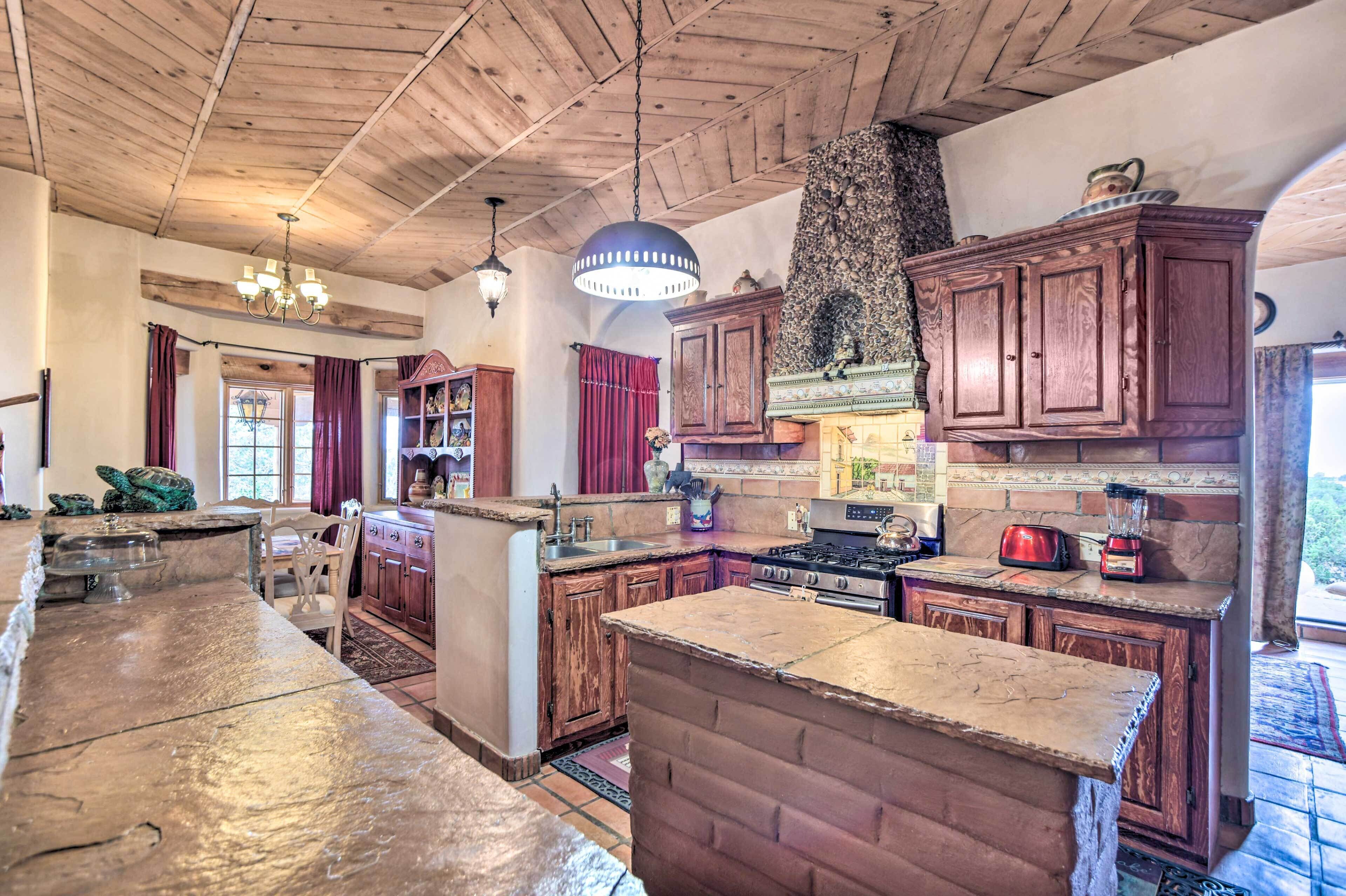 A spacious kitchen with wooden cabinets, a large island, and a stone fireplace.