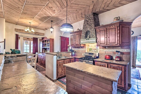 A spacious kitchen with wooden cabinets, a large island, and a stone fireplace.