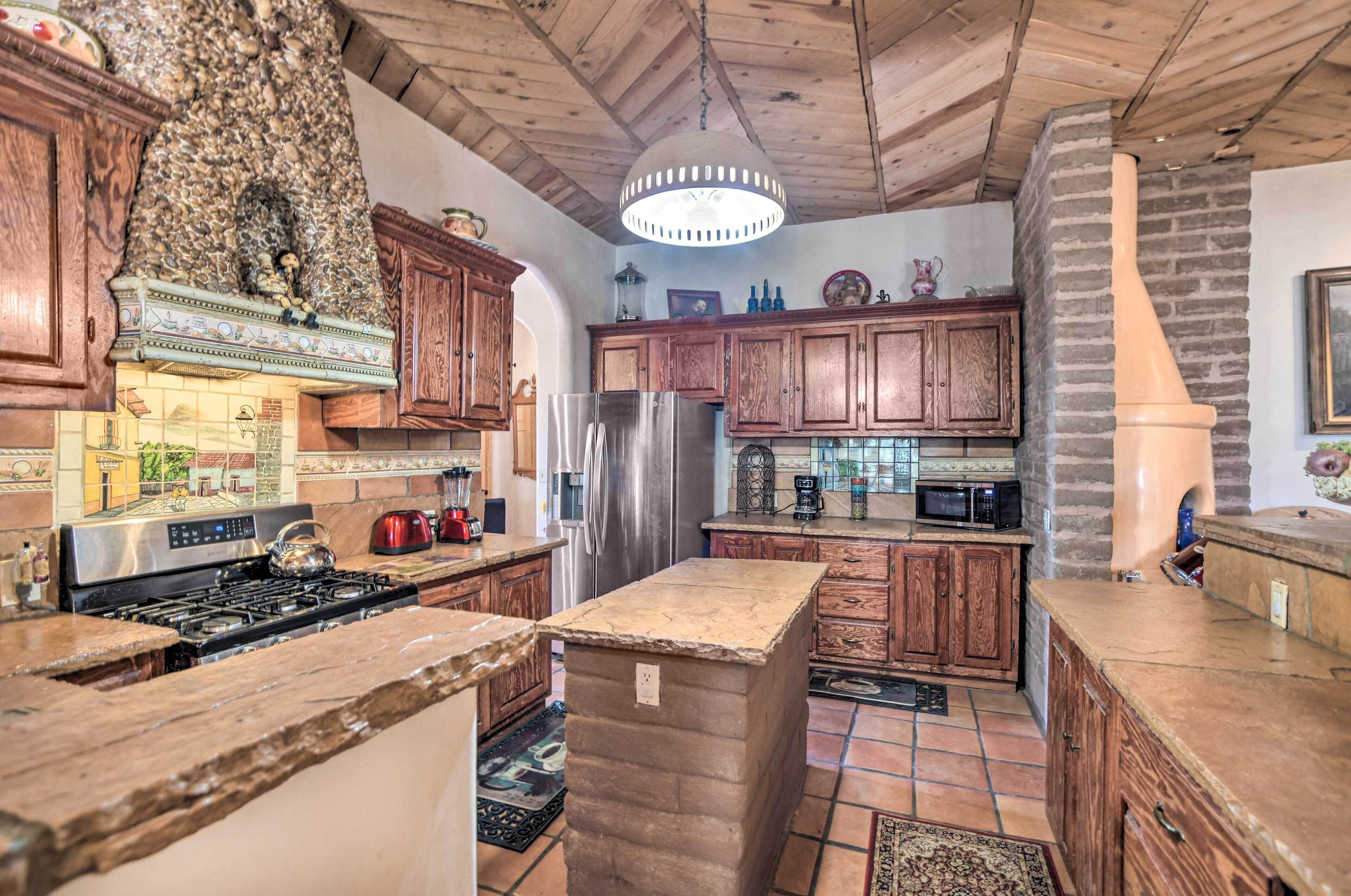 A kitchen with wooden cabinets, a stainless steel refrigerator, and a stone island.
