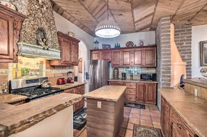 A kitchen with wooden cabinets, a stainless steel refrigerator, and a stone island.
