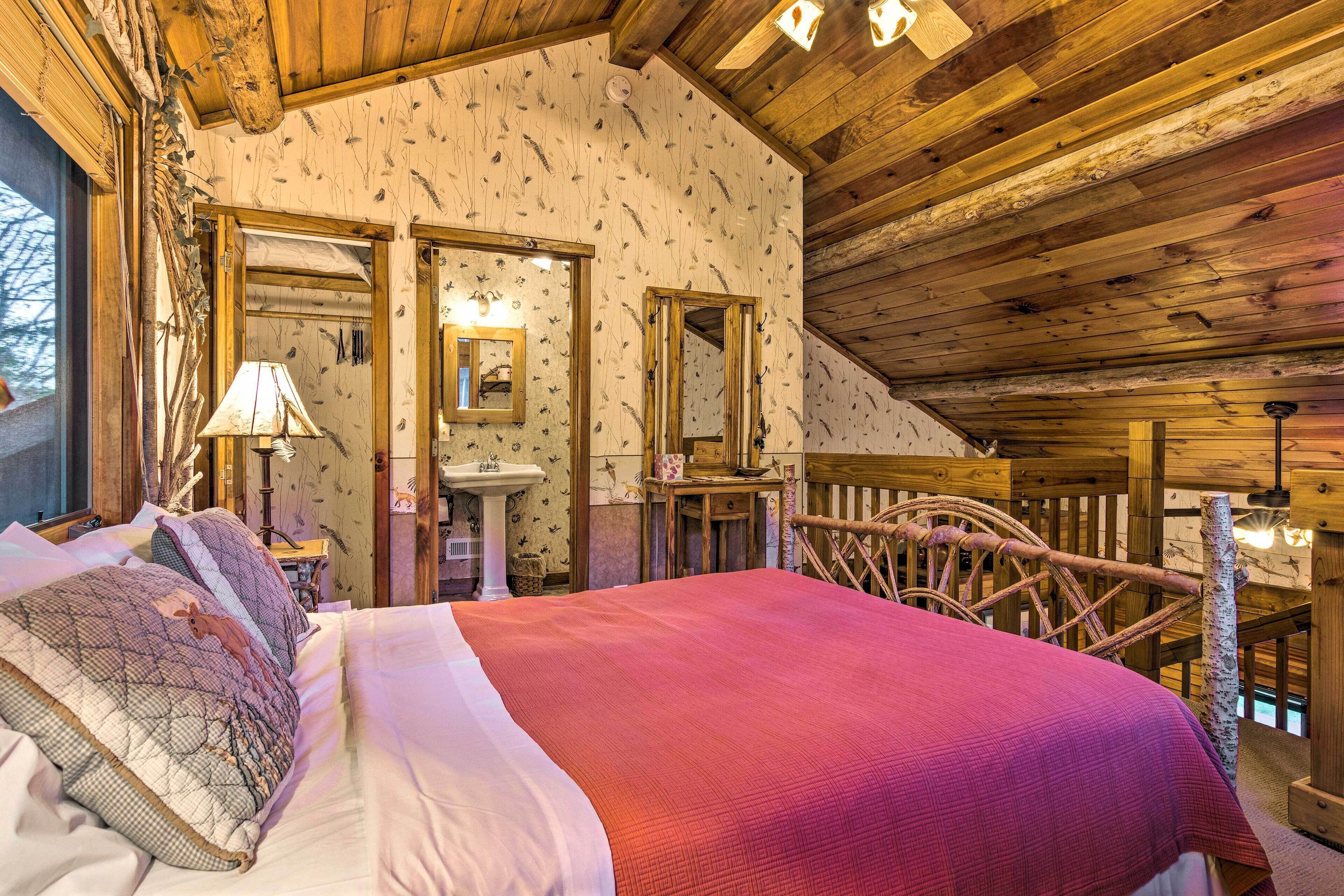 A wooden cabin bedroom with a bed, a dresser, a mirror, and a window.