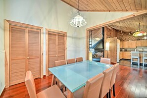 A dining area with a glass table and leather chairs, wooden cabinets, and a staircase leading to a loft.