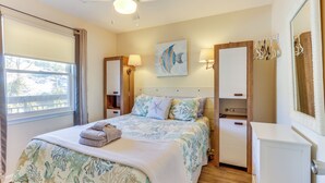 A bedroom with a bed, bedside lamps, a painting, a dresser, and a window with curtains. - Ocean-view Balcony: Beachfront Hilton Head Condo (Hilton Head Island)