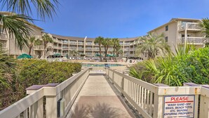A wooden walkway leading to a pool area with a sign requesting guests to wash off sand before entering. - Ocean-view Balcony: Beachfront Hilton Head Condo (Hilton Head Island)