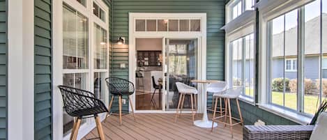 A covered porch with wooden flooring, a ceiling fan, and a view into the house.