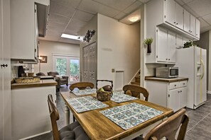 A modern kitchen with white cabinets, a wooden dining table with placemats, and a microwave on the counter. - Spacious Mcgaheysville Family Retreat w/ Game Room (McGaheysville)