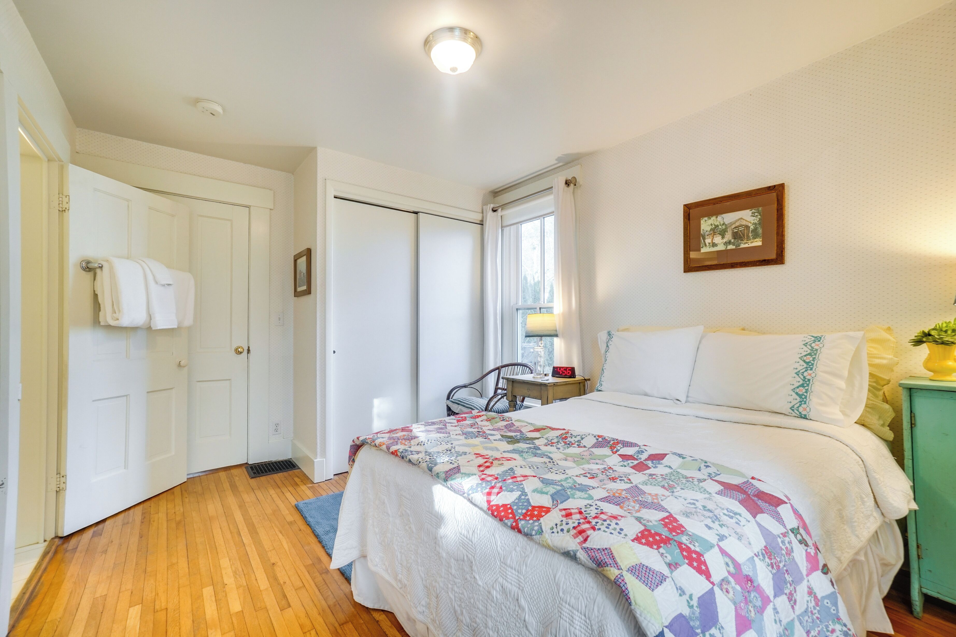 Une chambre à coucher avec un lit, une chaise, un bureau, une fenêtre et une porte.