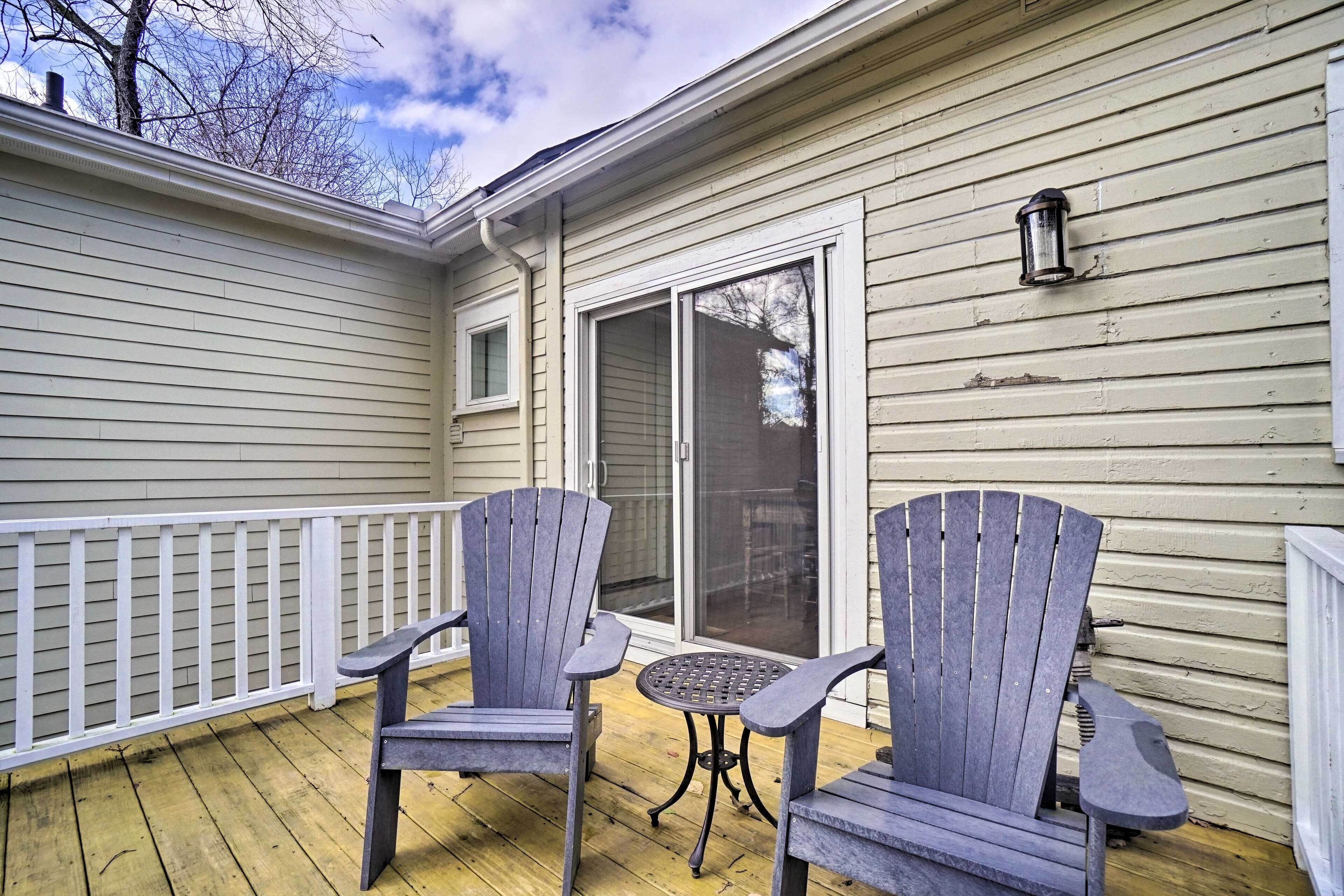 Eine überdachte Veranda mit zwei Adirondack-Stühlen und einem kleinen runden Tisch.