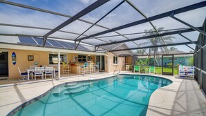 Ein Innenpool mit Glasdach, umgeben von einer Terrassenfläche mit Stühlen und einem Tisch.