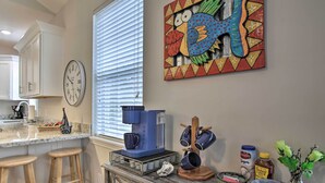 A kitchen with a coffee maker, mugs, a bowl, and a jar of honey on the counter.